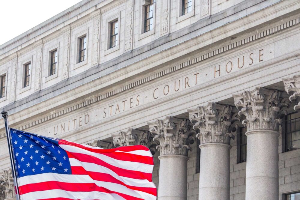 American flag infront of a courthouse blowing in the wind